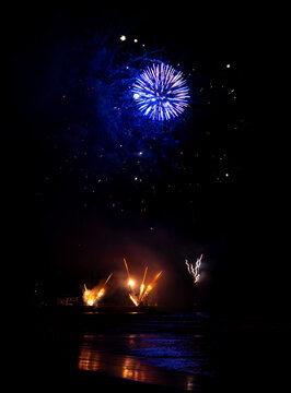 Blue fireworks burst over water at night