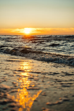 Golden sunset over ocean waves on a sandy beach