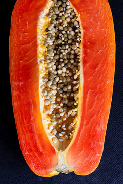 Halved ripe papaya with seeds on black background
