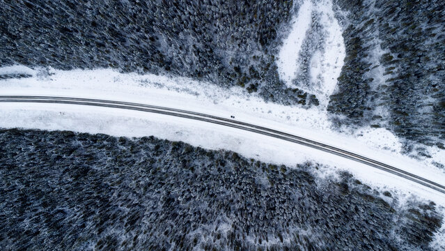 Aerial view of car on snowy highway in Alberta forest