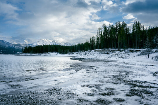 Frozen shoreline of Abraham Lake beneath snowy mountains