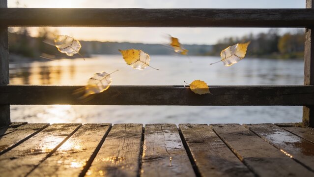 Drifting cluster of yellow autumn leaves fluttering above dock railing at lakeside, sun reflections