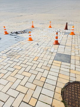 Damaged sidewalk paving tiles traffic cones warning repair city street road works hazard danger pedestrian infrastructure urban