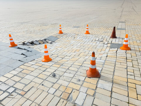Damaged sidewalk paving tiles traffic cones warning repair city street road works hazard danger pedestrian infrastructure urban