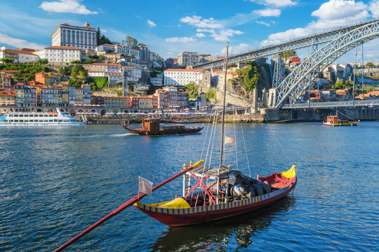 Rabelo boat moored near Porto Ribeira, Portugal, on the Douro River with wine barrels and Vila Nova de Gaia cityscape