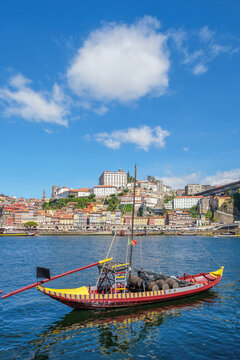Rabelo boat on the Douro River facing Porto Ribeira, Portugal, with old town architecture and Vila Nova de Gaia riverside