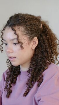 Vertical video: Lifting gaze youth smiling turning right laughing at home in mauve top, scrunchie