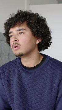 Vertical video: Making left turn, man tilting back yawning covering face in bedroom navy sweatshirt