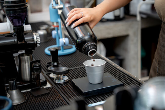 Close up of whole roasted beans falling into a cup during coffee preparation.
