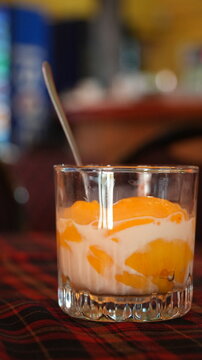 Postre cremoso con trozos de fruta naranja servido en vaso de vidrio