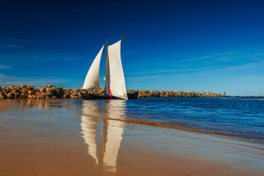 A sailboat with white sails in the beach of the Baltic sea