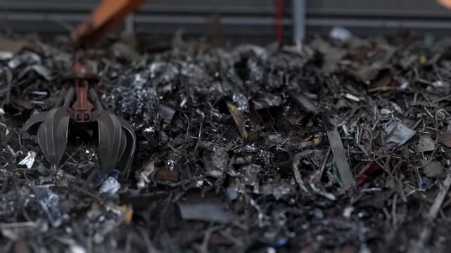 Crane grapple claw grabs scrap metal at steel mill, close up. Metal recycling, heavy industry