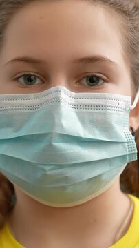 A girl wearing a blue mask looks directly at the camera. The girl&rsquo;s eyes are focused and serious, presenting a clear view of her expression during this time.