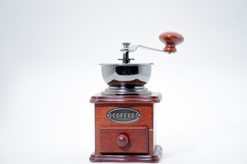 Vintage manual wooden coffee grinder with chrome metal bowl, crank handle, and drawer on clean white studio background with copy space, retro kitchen coffee mill with selective focus © Wicee