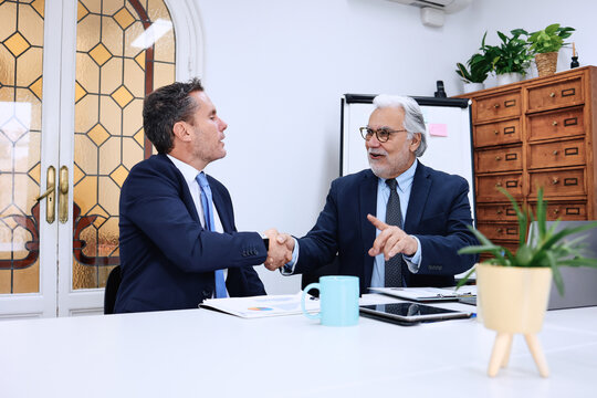 hispanic senior manager or boss and his business employee working at office, teamwork in a company or workplace