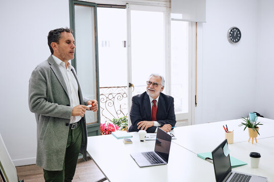 hispanic senior manager or boss and his business employee working at office, teamwork in a company or workplace