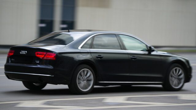 Black Audi A8L TFSI luxury sedan traveling along an urban road with panning blur, representing executive transportation, premium German engineering and business mobility
