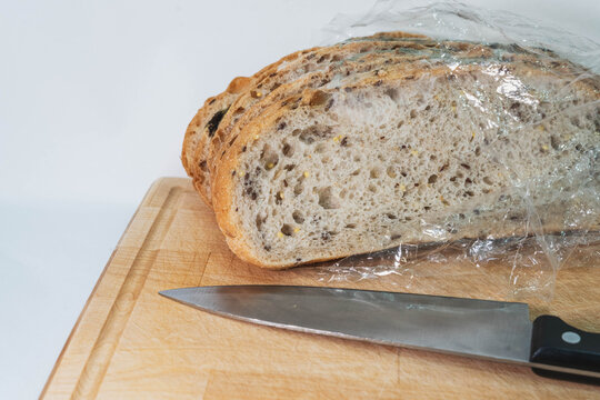 moldy bread slices display visible fungal contamination on kitchen cutting board beside large knife. spoiled bread exhibits green mildew, serving food safety inspection education purposes.