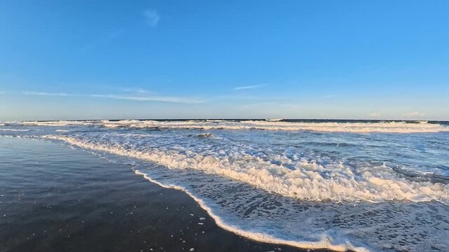  Atlantic surf rolls toward the camera beneath blue sky in this 4K video.
