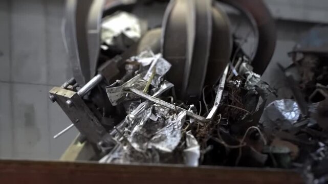 Crane claw loads scrap metal into container, close up. Metal recycling for steel smelting, heavy industry