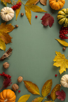 Autumn Thanksgiving flat lay with pumpkin, fall leaf, harvest nut and cinnamon on vertical green background