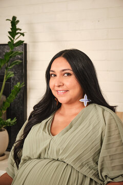 Native American pregnant woman in indoor setting with plants and soft lighting