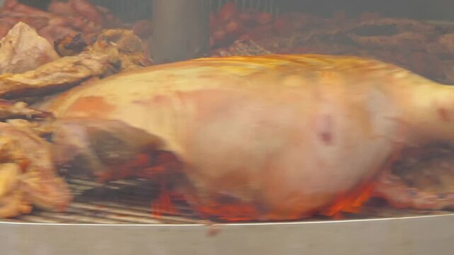 Rotating circular barbecue grill loaded with assorted Spanish meats including chorizo sausages, blood sausage morcilla, pork ribs, and steaks at a street food market.