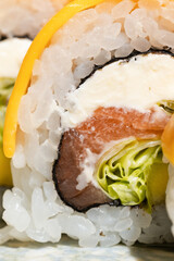 Extreme close-up of a Japanese sushi roll filled with salmon, cream cheese, rice and fresh vegetables, highlighting the delicate seafood layers and detailed food texture. © vision