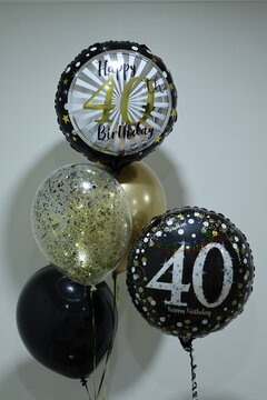 Black, gold and silver balloons celebrating a happy 40th birthday milestone with festive number 40 designs and party decorations.
