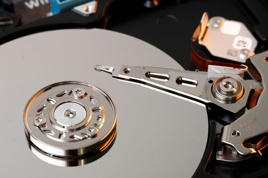 Detailed macro photography of a computer hard disk drive read write head resting on the shiny storage platter