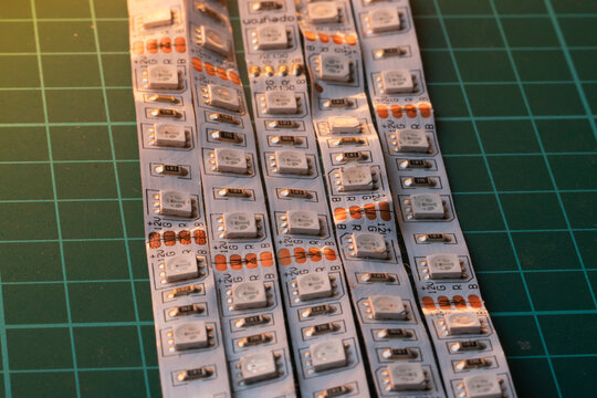 Rows of flexible rgb smd led light strips illuminated by warm side light on a green cutting mat background