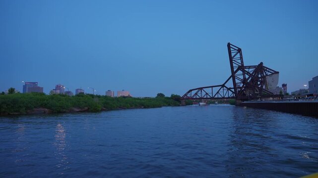 Historic steel lift bridge crossing the Chicago River during blue hour with calm water and distant city lights. Industrial bridge architecture and urban waterfront scenery create a dramatic evening