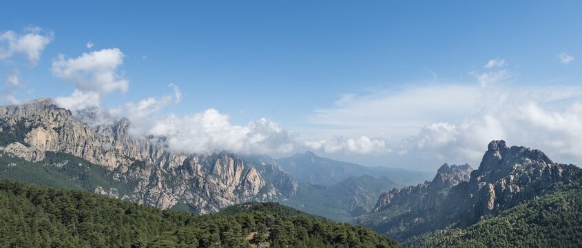Panoramic view over a valley, mountain slopes with rocky peaks surrounded by pine forests, cliffs, Col de Bavella, Bavella Massif, Corsica, France