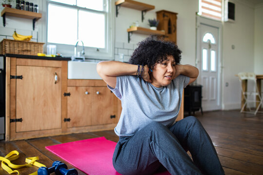 Woman doing sit-ups on mat in home kitchen