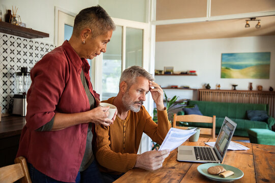 Concerned couple reviewing bills at the kitchen table