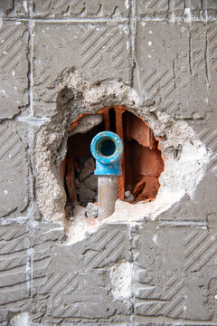 Blue PVC water pipe fitting exposed in wall opening. Focus on plumbing installation, piping, renovation, and construction.