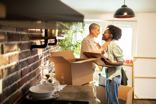 Two women share a loving moment while unpacking boxes in the kitchen