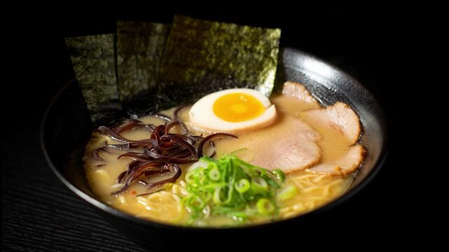 Delicious japanese tonkotsu ramen noodle soup with pork chashu, egg, and nori seaweed in a black bowl
