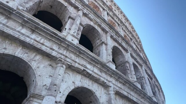 Weathered travertine facade with arches and columns of the Colosseum seen from below, Rome, Italy