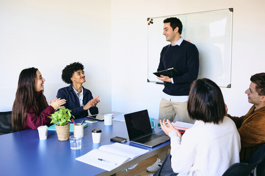 Diverse Group of young latin professionals engaged in a discussion at an office, hispanic teamwork using laptop at workplace