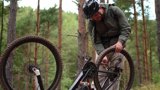 Fixing a flat tire while mountain biking in a serene forest setting