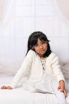 5 year old Latina brunette girl with eyeglasses among decorated trees is excited to celebrate Christmas and New Year