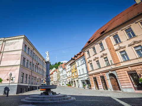 Fountain between Gornji trg and Levstikov trg in Ljubljana, Slovenia, surrounded by pastel historic buildings, red tiled roofs and cobbled paving in the pedestrian area of the capital city's old town.