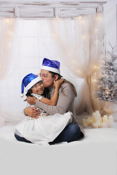 Divorced single mother and her 5-year-old Latina daughter with glasses excited celebrate Christmas and New Year's together, wearing Santa hats