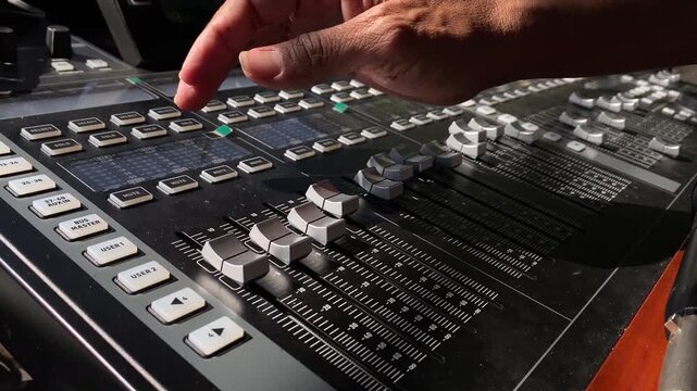 Close-Up of Sound Engineer Hand Sliding Faders on Digital Audio Mixing Console
