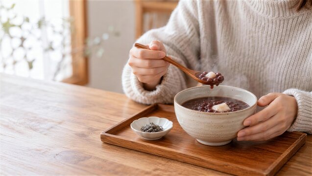餅入りのぜんざいを木のスプーンですくう手元