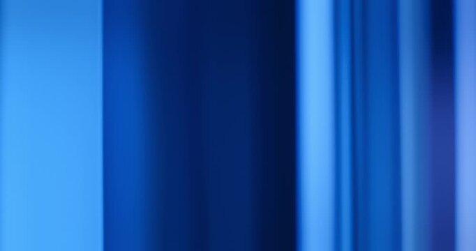 Radiant blue lights illuminate the brilliance of moving reflective glass creating a gradient of soft blues for a calm, relaxing aura. Smooth dreamy blue lighting abstract background or wallpaper Loop