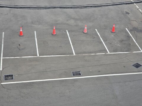High angle view of empty asphalt parking spaces with orange traffic cones