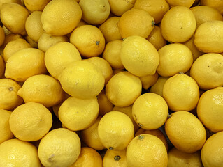 Close up of fresh yellow lemons piled together,showcasing their bright color and textured peels.Ideal for food backgrounds,healthy eating,citrus fruit,agriculture,nutrition,and grocery market concepts © Gabie
