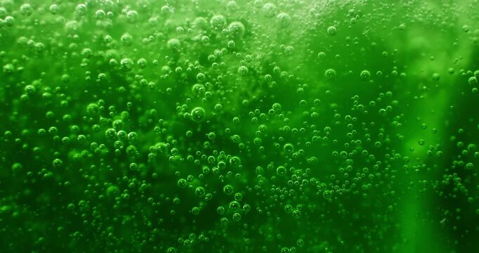 Green liquid with bubbles and fizz with a swirl of a turbulent chemical reaction. Green background for a festive St Patrick's day drink or a scary witches brew for eerie Halloween backgrounds.